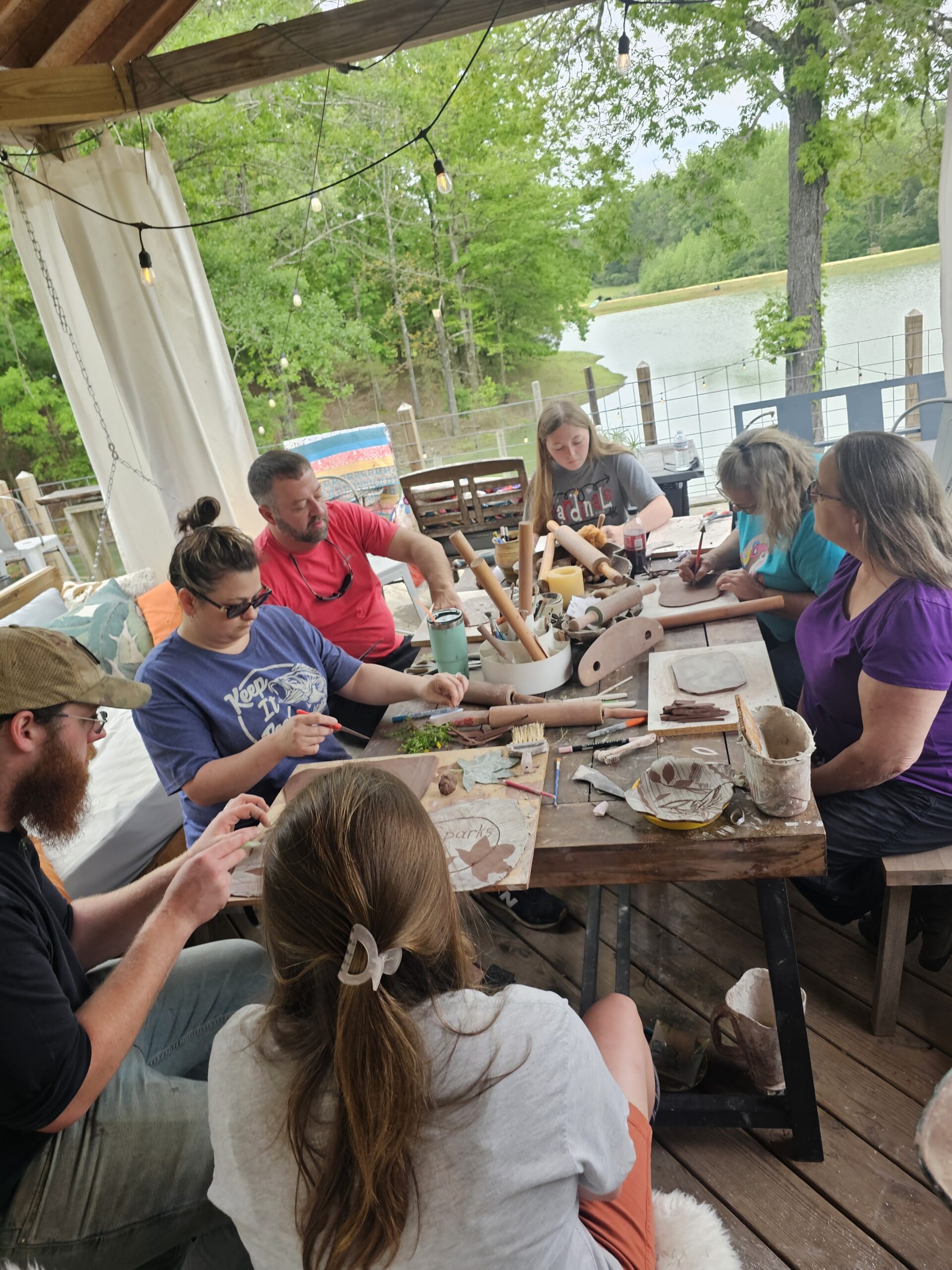 Workshop guests shaping clay together at a long table